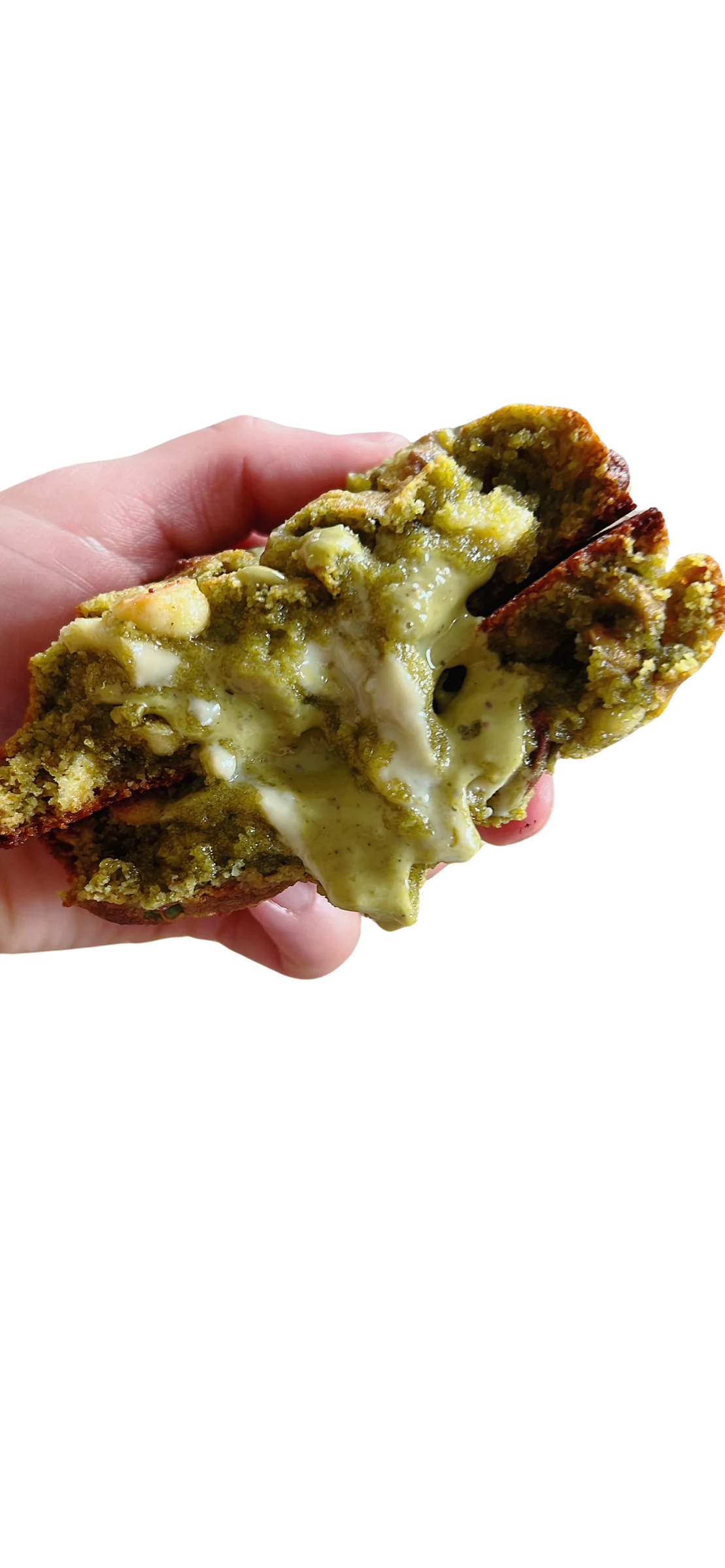 Galleta keto de matcha y pistacho partida a la mitad, con relleno de crema de pistacho verde estirándose entre las dos mitades
