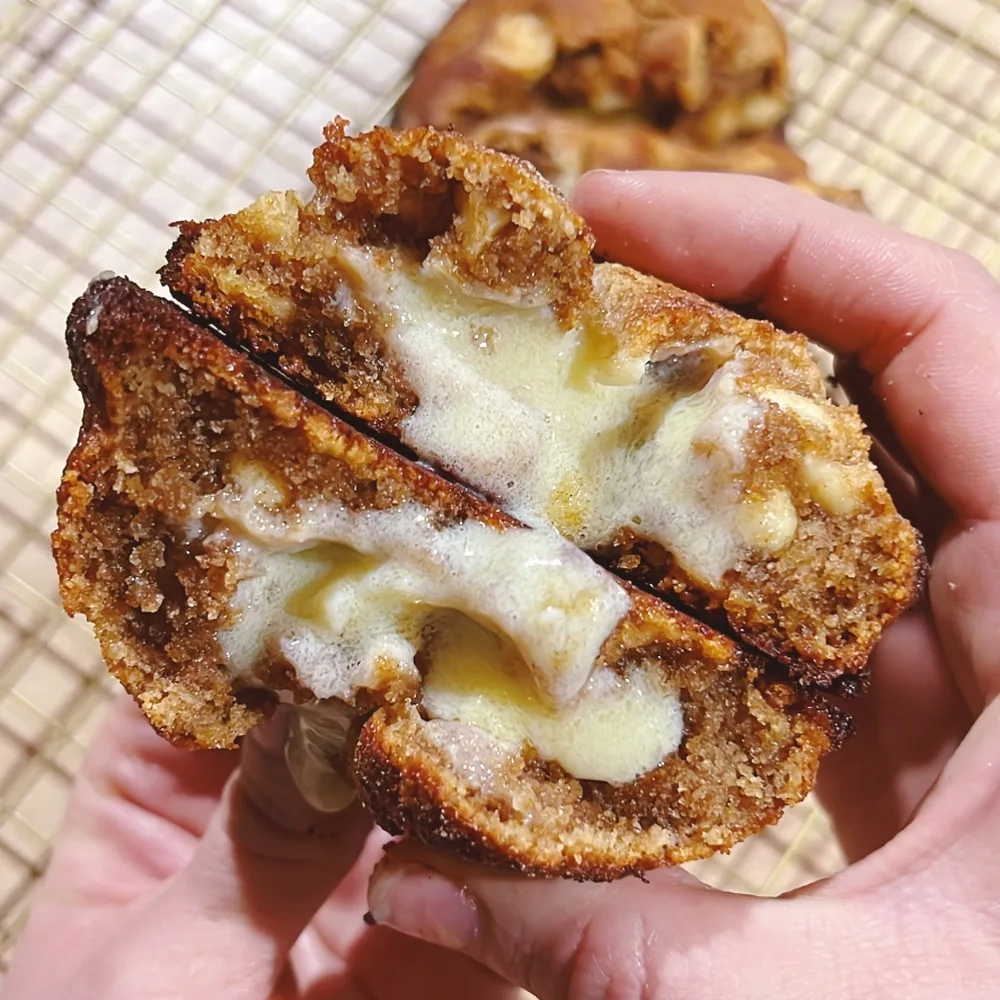 Galleta keto de cinnamon roll partida, con la crema de canela visible en el centro