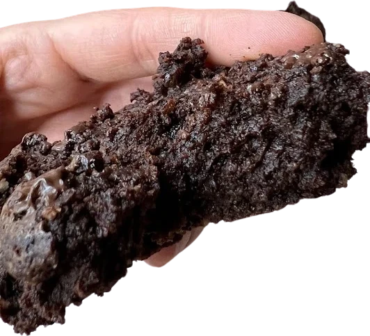 Galleta keto de chocolate negro y menta de miga muy oscura sostenida entre los dedos